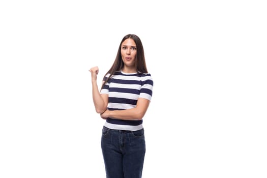 attractive young caucasian brunette woman in a striped t-shirt points with her hands to the advertising space on a white background with copy space.