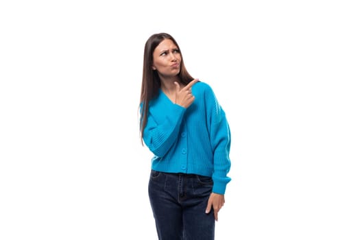 young beautiful european brunette woman dressed in a blue cardigan gesturing with her hands pointing space for advertising.