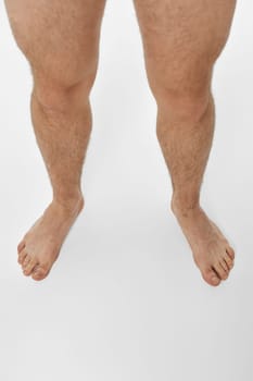 Barefoot male legs on white background. top view