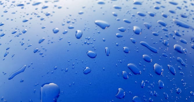 Drops of rainwater on blue metal background after nanoceramics polishing technology closeup