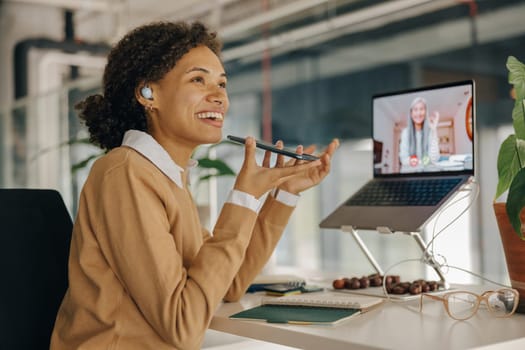 Smiling business woman have video conference with client and record audio message sitting in office