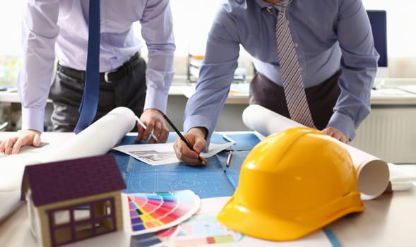 Architect Engineer Sketching Construction Project. Building Design Concept. Engineering Hand Holding Pencil Designing Structure on Blueprint. Drawing with Yellow Helmet at Workplace