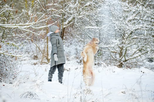 Teenage Girl With Golden Retriever Plays With Snow In Winter Forest