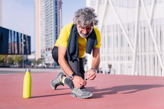 senior sports man tying his running shoes before workout, concept of healthy and active lifestyle in middle age