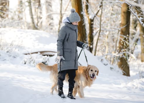 Teenage Girl With Golden Retriever Walks Through Snow-Covered Forest In Winter