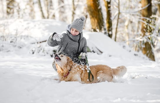 Teenage Girl Plays With Golden Retriever In Snowy Forest, Sitting With Dog