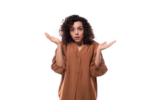 young fashionista curly brunette woman dressed in brown blouse doubts.