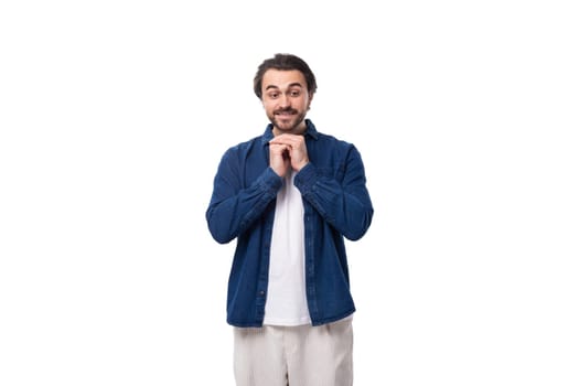 young positive handsome caucasian man with black hair is dressed in a blue shirt on a white background.