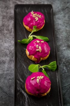 dessert of baked buns with raspberry topping and seed decorations