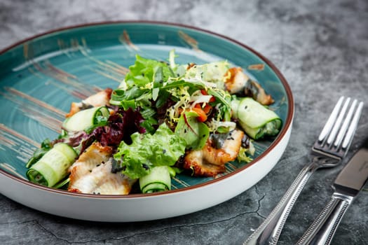 salad with arugula, lettuce, cucumber rolls, fish and sesame seeds