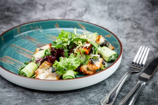 salad with arugula, lettuce, cucumber rolls, fish and sesame seeds