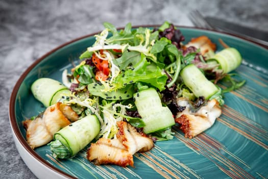 salad with arugula, lettuce, cucumber rolls, fish and sesame seeds