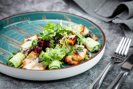 salad with arugula, lettuce, cucumber rolls, fish and sesame seeds