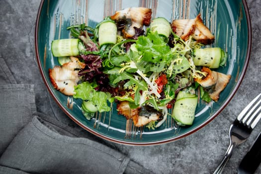 salad with arugula, lettuce, cucumber rolls, fish and sesame seeds