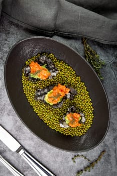 black caviar, red fish and wassabi on a plate with peas