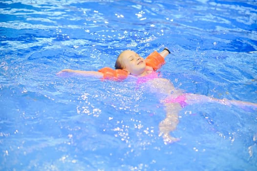 Cute girl with inflatables swimming in the pool. Healthy sport for children.