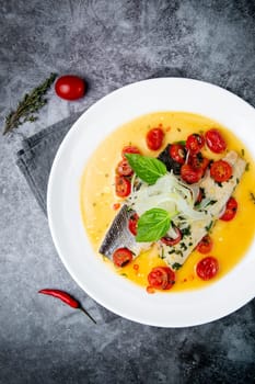 unpeeled fish with gravy, herbs, cherry tomatoes and onions