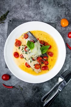 unpeeled fish with gravy, herbs, cherry tomatoes and onions