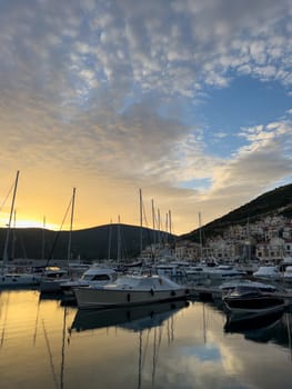 Sunset behind the mountains over the marina with moored yachts. High quality photo