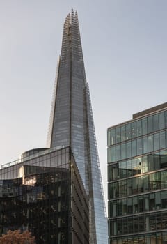 London, UK - Nov 07, 2023 - The Shard Tower in London with surrounding corporate buildings with sky background. View of the shard skyscraper in london, Vivid blue and turquoise office building with plate glass walls and gleaming steel structure, Space for text, Selective Focus.