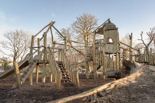 The Children's playground with Slide, Rope Net Bridge made of Wooden Tree trunk in acton park. Empty outdoor playground with wooden equipment for children, Space for text, Selective focus.