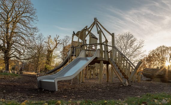 The Children's playground with Slide, Rope Net Bridge made of Wooden Tree trunk in acton park. Empty outdoor playground with wooden equipment for children, Copy space, Selective focus.
