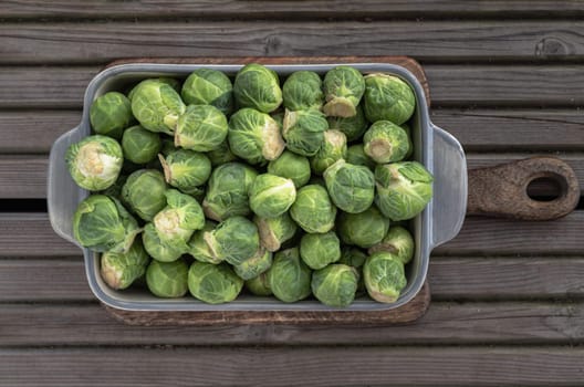 Fresh raw organic Green brussel sprouts vegetable on Wooden cutting board with Natural sunlight. Uncooked brussels sprouts, View from above, Space for text, Selective focus.