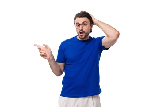 young brunette european man with a beard in a blue t-shirt looks away on a white background with copy space.