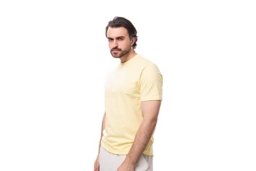 caucasian brutal charming guy with a beard dressed in a summer t-shirt on a white background with copy space.