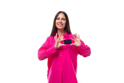 happy positive young brunette lady dressed in bright pink shirt holding plastic credit card.