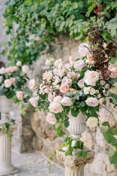 Bouquet of flowers stands in a vase on a pedestal in the garden. High quality photo