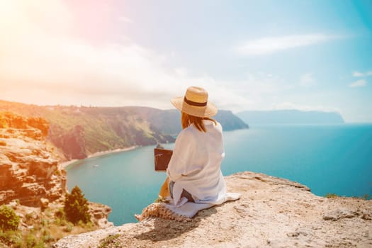 Freelance woman working on a laptop by the sea, typing away on the keyboard while enjoying the beautiful view, highlighting the idea of remote work