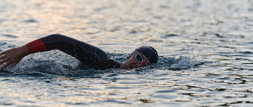 A professional triathlete trains with unwavering dedication for an upcoming competition at a lake, emanating a sense of athleticism and profound commitment to excellence