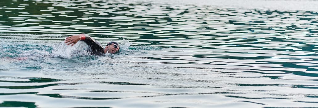 A professional triathlete trains with unwavering dedication for an upcoming competition at a lake, emanating a sense of athleticism and profound commitment to excellence