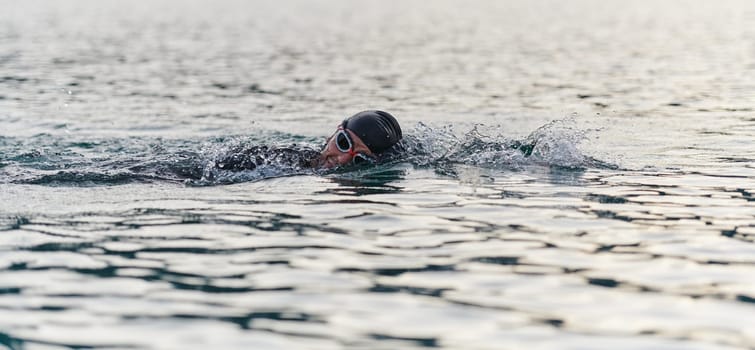 A professional triathlete trains with unwavering dedication for an upcoming competition at a lake, emanating a sense of athleticism and profound commitment to excellence