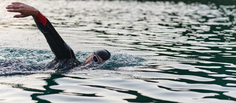 A professional triathlete trains with unwavering dedication for an upcoming competition at a lake, emanating a sense of athleticism and profound commitment to excellence