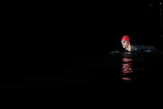 Authentic triathlete swimmer having a break during hard training on night.