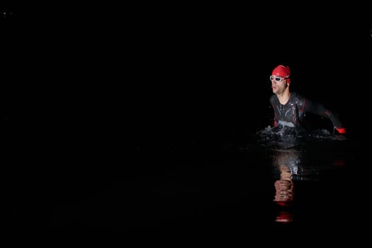 Authentic triathlete swimmer having a break during hard training on night.