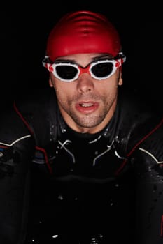 A determined professional triathlete undergoes rigorous night time training in cold waters, showcasing dedication and resilience in preparation for an upcoming triathlon swim competition.