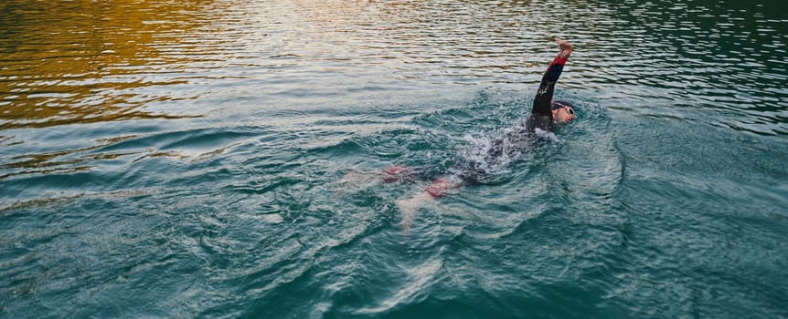 A professional triathlete trains with unwavering dedication for an upcoming competition at a lake, emanating a sense of athleticism and profound commitment to excellence