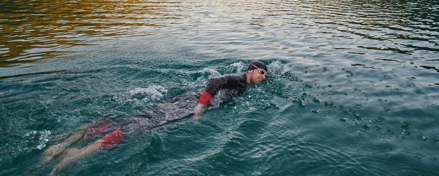 A professional triathlete trains with unwavering dedication for an upcoming competition at a lake, emanating a sense of athleticism and profound commitment to excellence