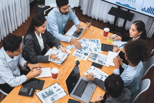 Multiracial analyst team use BI dashboard data to analyze financial report on meeting table. Group of diverse business people utilize data analysis by FIntech for success business marketing. Concord