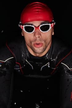 A determined professional triathlete undergoes rigorous night time training in cold waters, showcasing dedication and resilience in preparation for an upcoming triathlon swim competition.