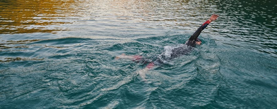 A professional triathlete trains with unwavering dedication for an upcoming competition at a lake, emanating a sense of athleticism and profound commitment to excellence