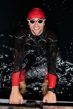 Authentic triathlete swimmer having a break during hard training on night.