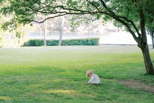 Little girl sits on a green meadow and picks wild flowers. High quality photo