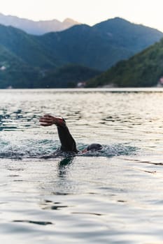 A professional triathlete trains with unwavering dedication for an upcoming competition at a lake, emanating a sense of athleticism and profound commitment to excellence