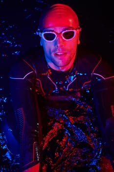 real triathlete swimmer having a break during hard training at lake on dark night neon gel color lights