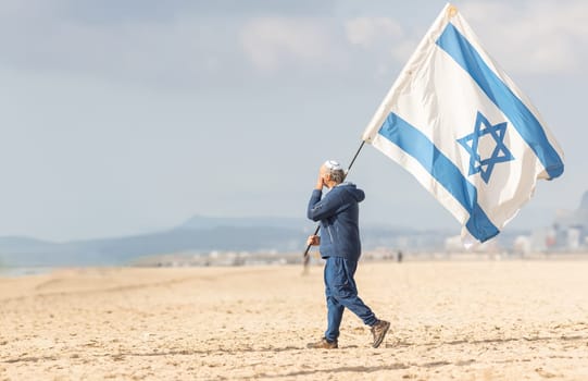 25 november 2023, Lisbon, Portugal - A Man Walking on a Beach Holding a Flag of Israel - yelephoto