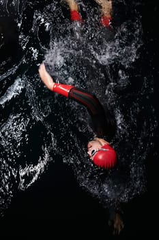 A determined professional triathlete undergoes rigorous night time training in cold waters, showcasing dedication and resilience in preparation for an upcoming triathlon swim competition.